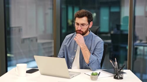 Businessman Works on Laptop in Modern Office Focused on Computer Task