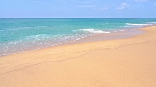 Wide golden sandy beach and calm turquoise sea of tropical island paradise. Slow motion view of litt
