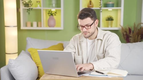 The man, whose eyes hurt from working, takes off his glasses and starts rubbing his eyes.
