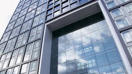Tall Modern Glass Building With Cloud Reflections on Windows in Bright Daylight