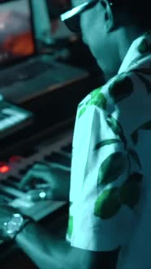 Audio engineer or producer working in a music recording studio with blue LED light playing the piano