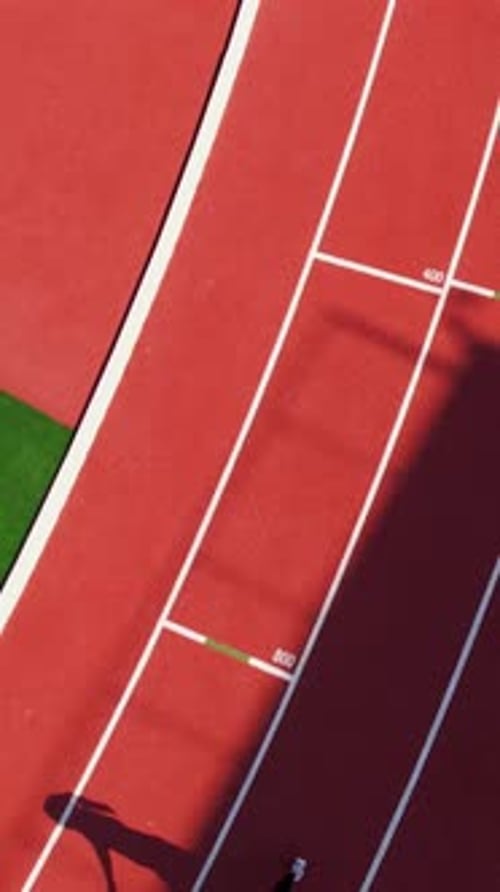 Aerial Vertical Shot Of Female Athlete Running On Red Stadium Track