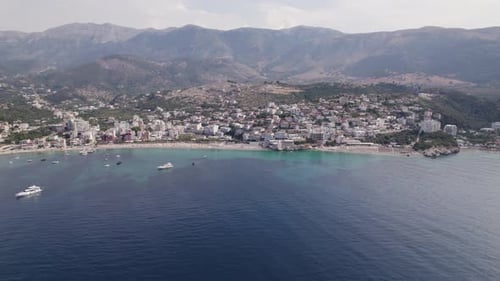 Picturesque coastal town on Albanian Riviera - Himarë, Albania; aerial arc