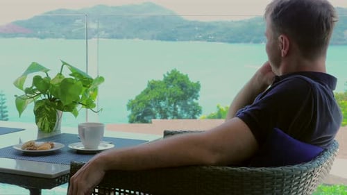 A Relaxed Man Enjoys His Lunch Break in a Hotel Cafe Terrace with a Sea View