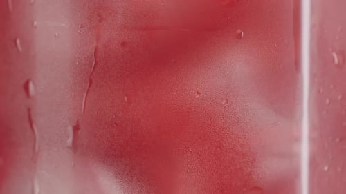 Cóctel rojo frío con cubitos de hielo y condensación