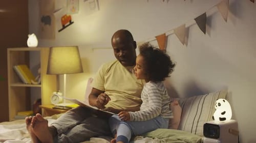 Man Reading Bedtime Story to Child on Bed