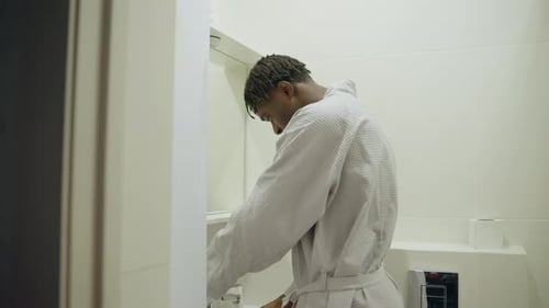 Man Washing Face in Small White Bathroom