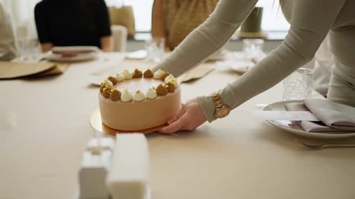 Woman Centers a Beautiful Cake at Party Table