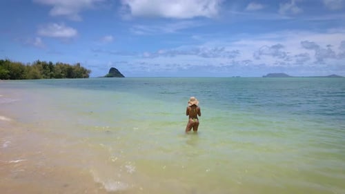 Paradise vibes: A sexy girl in a yellow bikini and straw hat enjoys the sea, symbolizing travel, tou