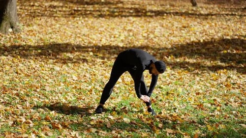 Young Man Stretching Outdoors in Autumn Park