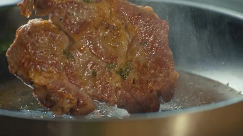 Close Up Professional Chef Turns Over with Tongs Piece of Meat Frying on a Pan