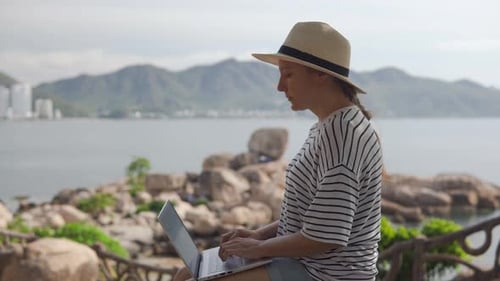 Woman working on laptop near the sea