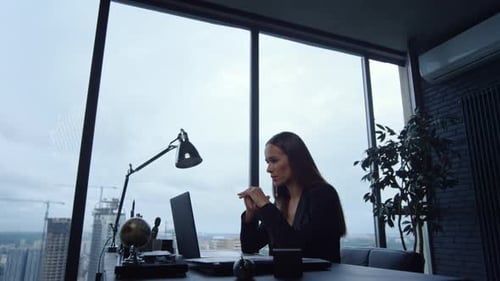 Confident businesswoman gesturing during online video call on laptop in modern office