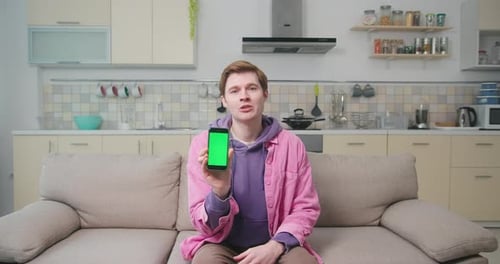 Young Adult Presenting a Phone with Green Screen