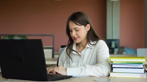 Smiling Girl with Headset Studying Online Using Laptop at University Taking Notes Copy Space