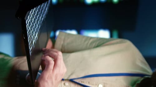 Person Using Laptop in Dimly Lit Workplace