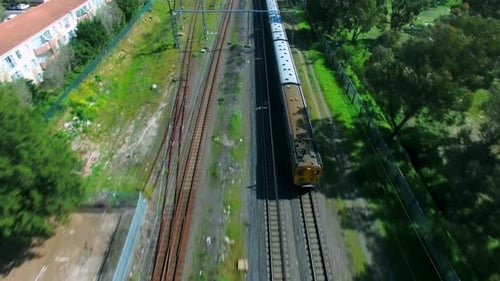 4K aerial drone footage of a passenger train riding on tracks in the city