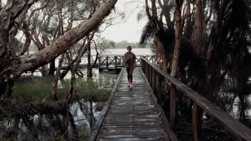 Woman Jogging on Wooden Path in Rural Setting