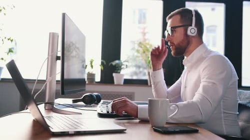 Man at Computer with Headset in Bright Office