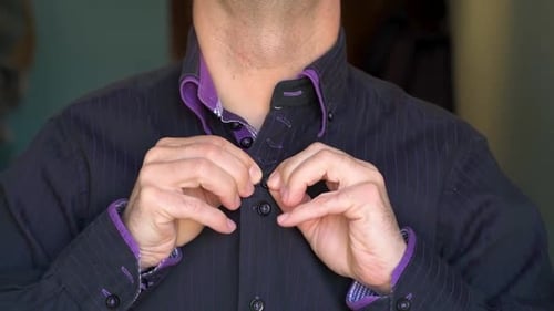 Man Buttoning Black and Purple Striped Dress Shirt