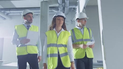 Team of Engineers in Hard Hats Walking and Talking, inside Building Under Construction.