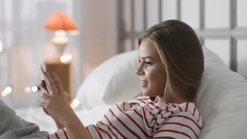 Woman Relaxing in Bed Using Smartphone