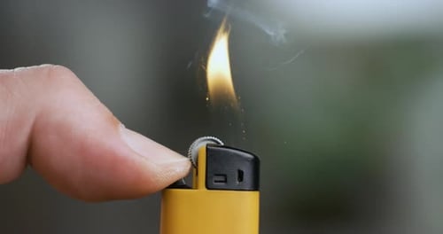 Hand lights the lighter. Blazing lighter in hand on super slow motion.