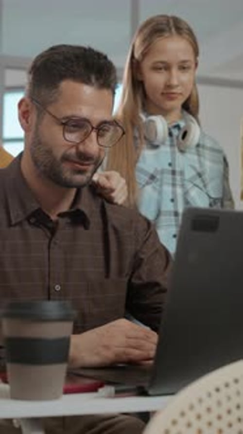 Teacher Sitting at Desk with Laptop Having Discussing with Teenagers
