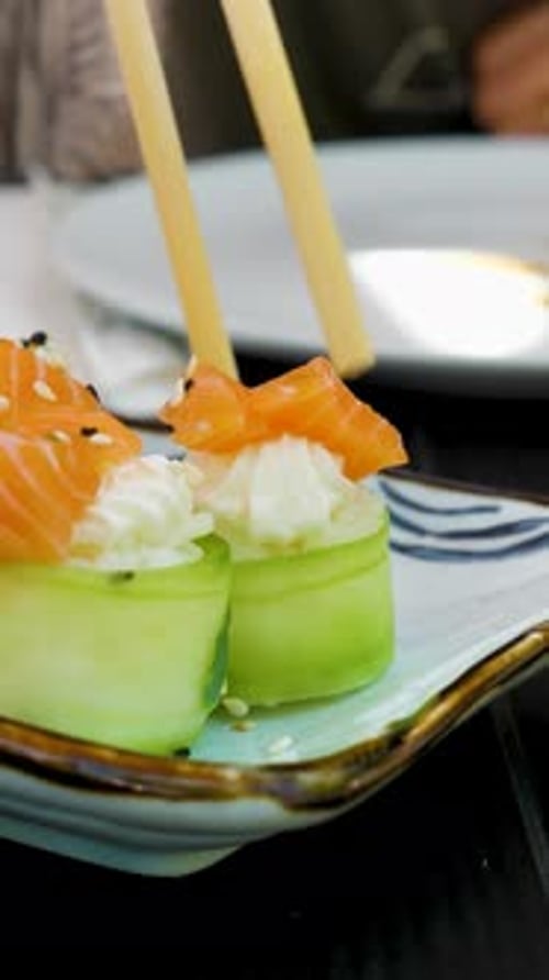 Eating sushi at a restaurant with chopsticks.