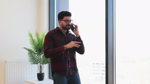 Young Man Talking on Phone in Modern Office Setting