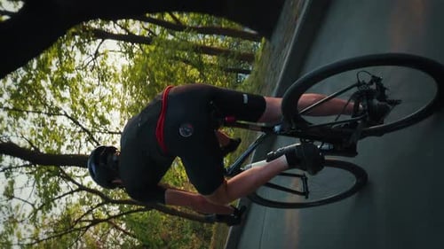 Professioneller athletischer Radfahrer, der im grünen Park den Hügel hinunterfährt. Vertikales Video