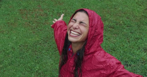 Woman Laughing in Rain Wearing Red Raincoat