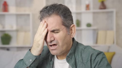 Ein reifer Mann mit medizinischen Gesundheitsproblemen hat Kopfschmerzen.