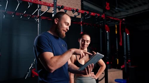 Trainer and Athlete with Tablet in Gym