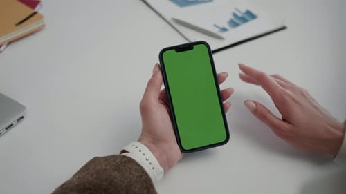 Young Lady Hand Taps on a Screen with a Green Screen on the Office Table Background