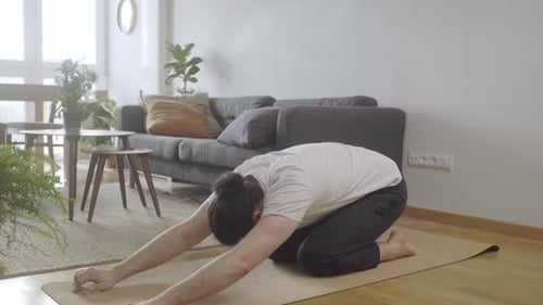 Man Stretching on Yoga Mat in Brightly Lit Home