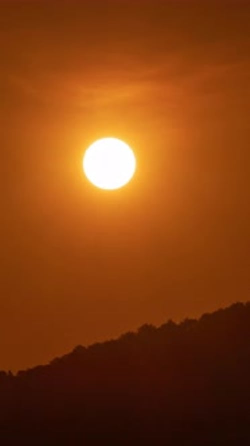Sun Sets Behind Mountain Silhouette in Golden Light