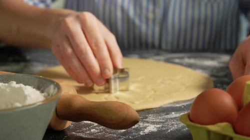 Woman cutting dough with cookie cutter close-up shot