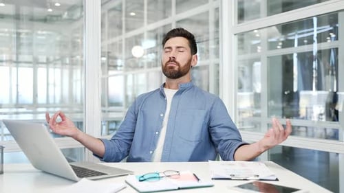 Man Meditating at Desk in Bright Office