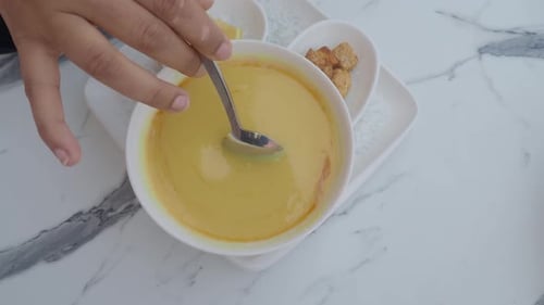 Creamy Soup Being Stirred with Spoon in Bowl