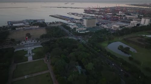 Forwards Fly Above Park Rizal Tilt Up Reveal Sea Coast and Charge Harbor with Big Cranes and Ships