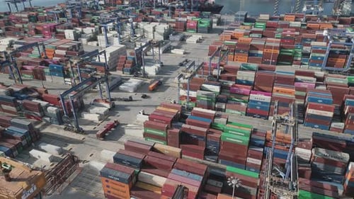 Aerial View of a Container Terminal with Cranes and Trucks in Action