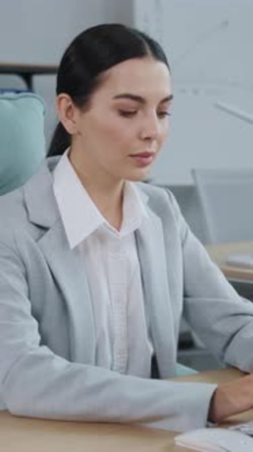 A Focused and Determined Businesswoman is Diligently Working at Her Desk in a Modern Office