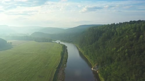 River Crossing Lush Green Valley Under Blue Sky