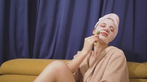 Woman uses Facial Roller with Face Mask