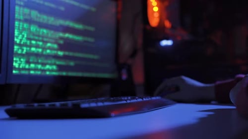 Male hacker doing cyber attack in a dark gloomy room with screen.