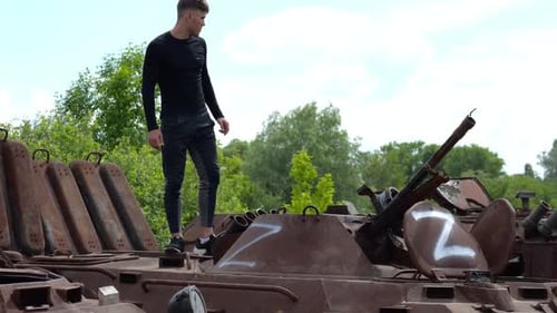 Man Standing on a Rusty Military Tank