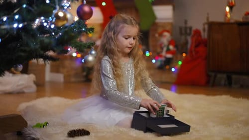 Young Girl Unboxing Christmas Presents by Festive Tree