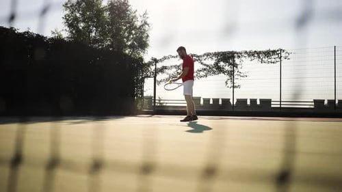 Man Practices Tennis Serve on Bright Outdoor Court