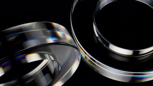 Rotating glass rings with iridescent edges on black background